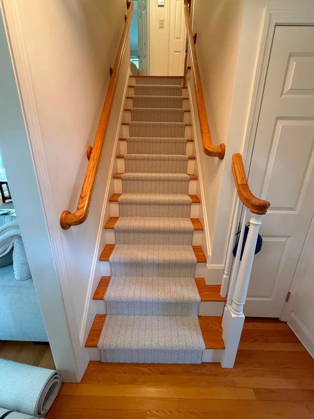 Patterned stair runner centered on wood steps with exposed edges and white risers.